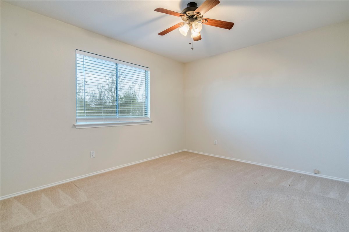 267 Carolyns Way Buda, TX 78610 - Photo 20 of 31 an empty room with a chandelier fan and windows