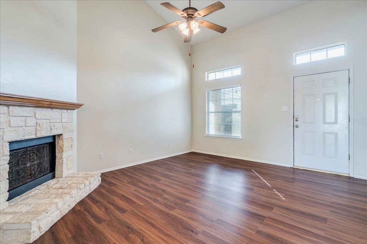 267 Carolyns Way Buda, TX 78610 - Photo 9 of 31 a view of an empty room with wooden floor fireplace and a window