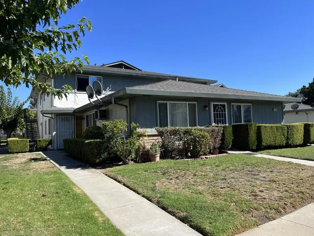 a front view of a house with a yard and potted plants