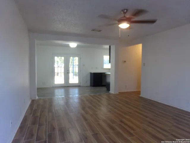 a view of empty room with wooden floor and fan