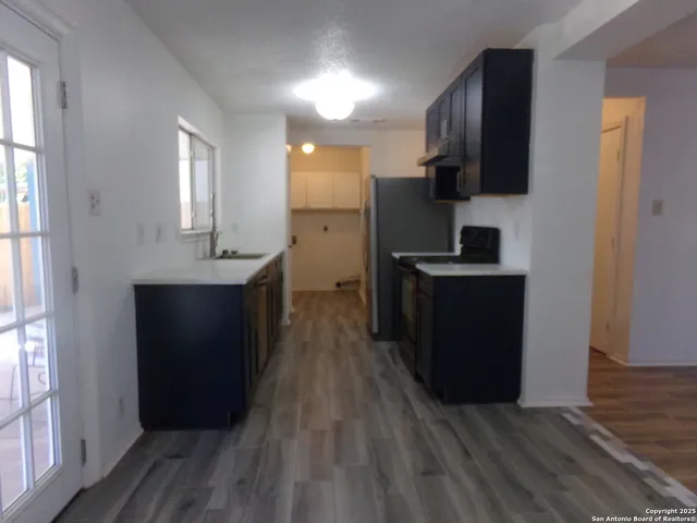 a kitchen with stainless steel appliances granite countertop a refrigerator a sink dishwasher and wooden cabinets with wooden floor