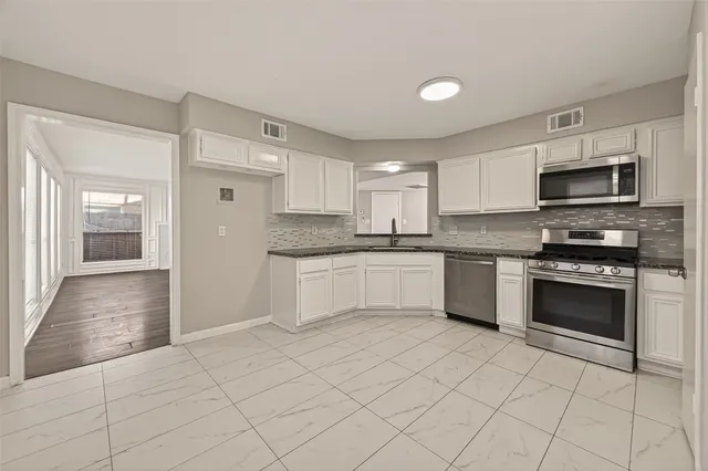 a kitchen with stainless steel appliances granite countertop a sink and dishwasher a refrigerator with white cabinets
