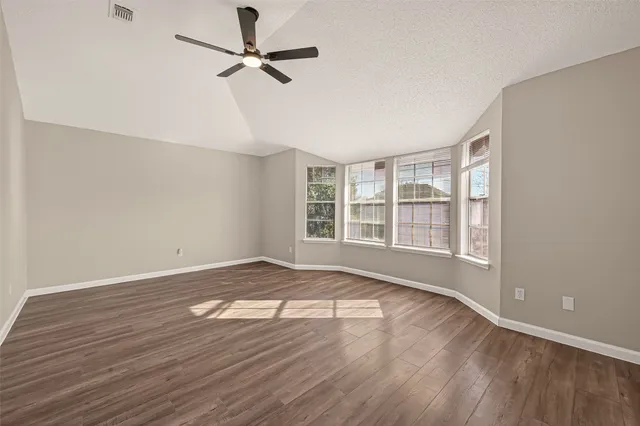 an empty room with wooden floor and windows