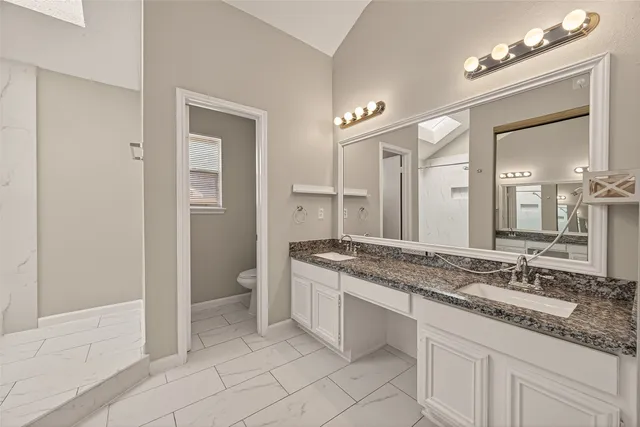 a spacious bathroom with a granite countertop sink a mirror and a toilet