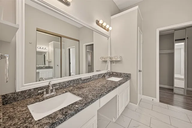 a bathroom with a granite countertop sink and a mirror