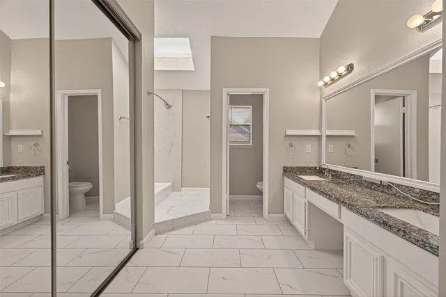 a spacious bathroom with a granite countertop sink a mirror and a shower