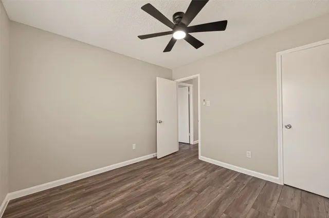 an empty room with wooden floor and a ceiling fan