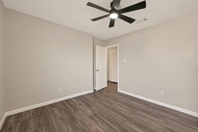 an empty room with wooden floor and ceiling fan