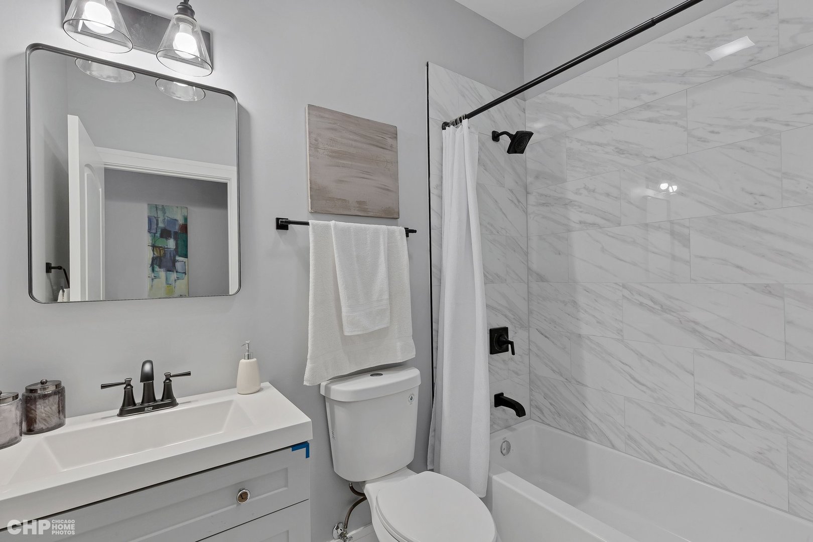 3920 South Calumet Avenue, Unit 2 Chicago, IL 60653 - Photo 19 of 24 a bathroom with a sink toilet a mirror and shower
