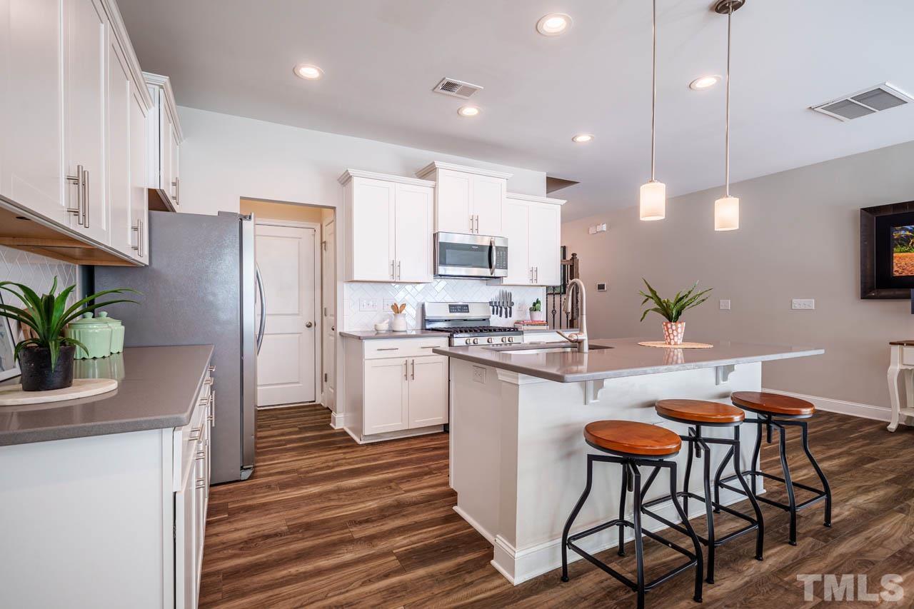 1007 Longitude Drive Durham, NC 27713 - Photo 10 of 35 a kitchen with stainless steel appliances kitchen island granite countertop a refrigerator a stove a sink dishwasher and a dining table with wooden floor