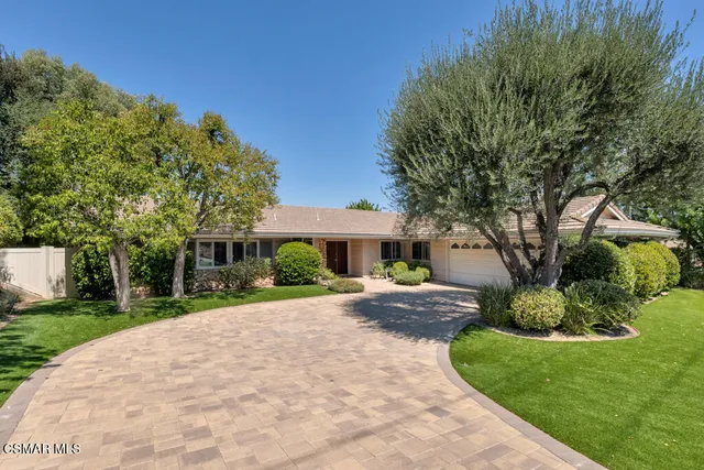 a front view of a house with a yard and potted plants
