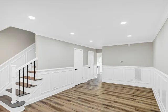 a view of an empty room with wooden floor and stairs