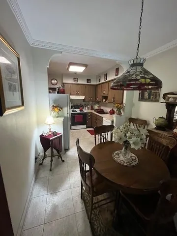 a view of a dining room and livingroom with furniture wooden floor a rug a painting and a chandelier