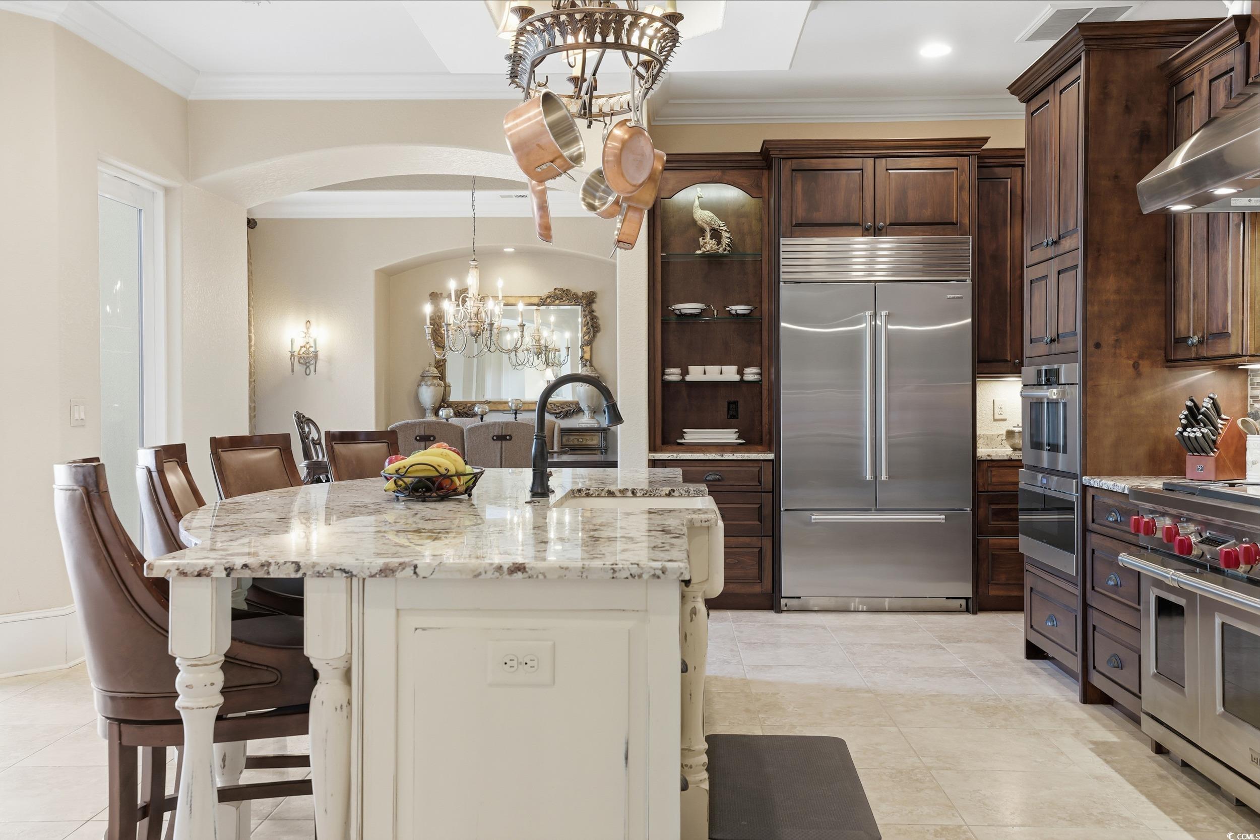 9552 Lugano Court Myrtle Beach, SC 29579 - Photo 11 of 40 Kitchen featuring high end appliances, light stone countertops, a kitchen breakfast bar, a chandelier, and ornamental molding