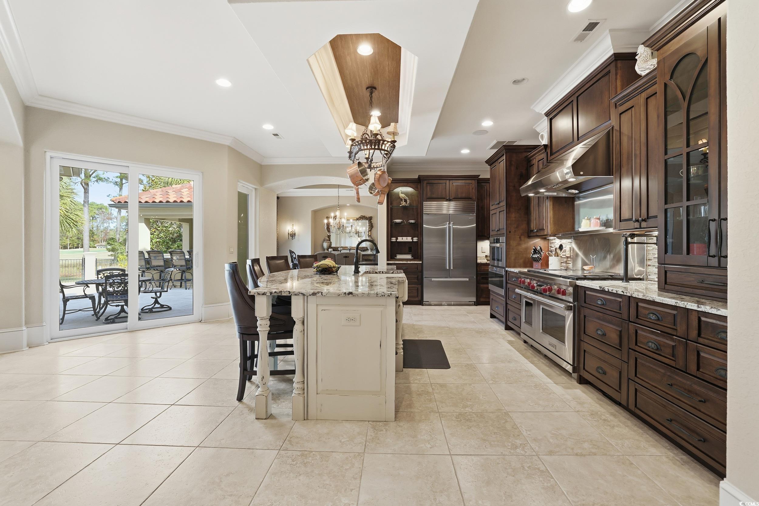 9552 Lugano Court Myrtle Beach, SC 29579 - Photo 12 of 40 Kitchen with arched walkways, a breakfast bar, light stone counters, a chandelier, and pendant lighting