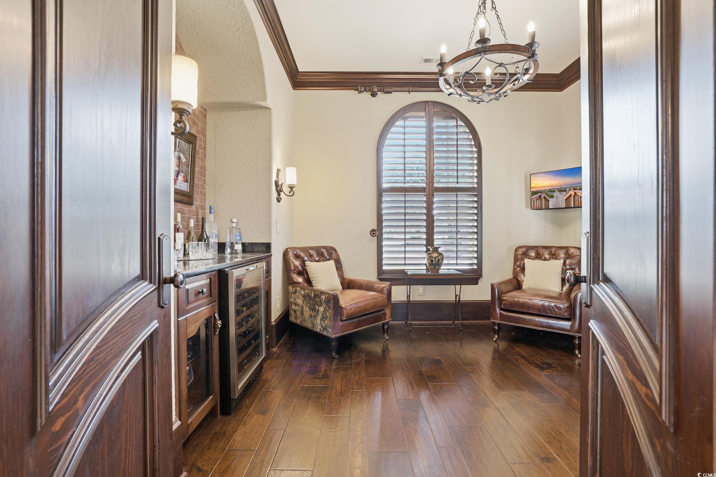 9552 Lugano Court Myrtle Beach, SC 29579 - Photo 16 of 40 Sitting room featuring ornamental molding, wine cooler, dark wood-style flooring, a chandelier, and a bar