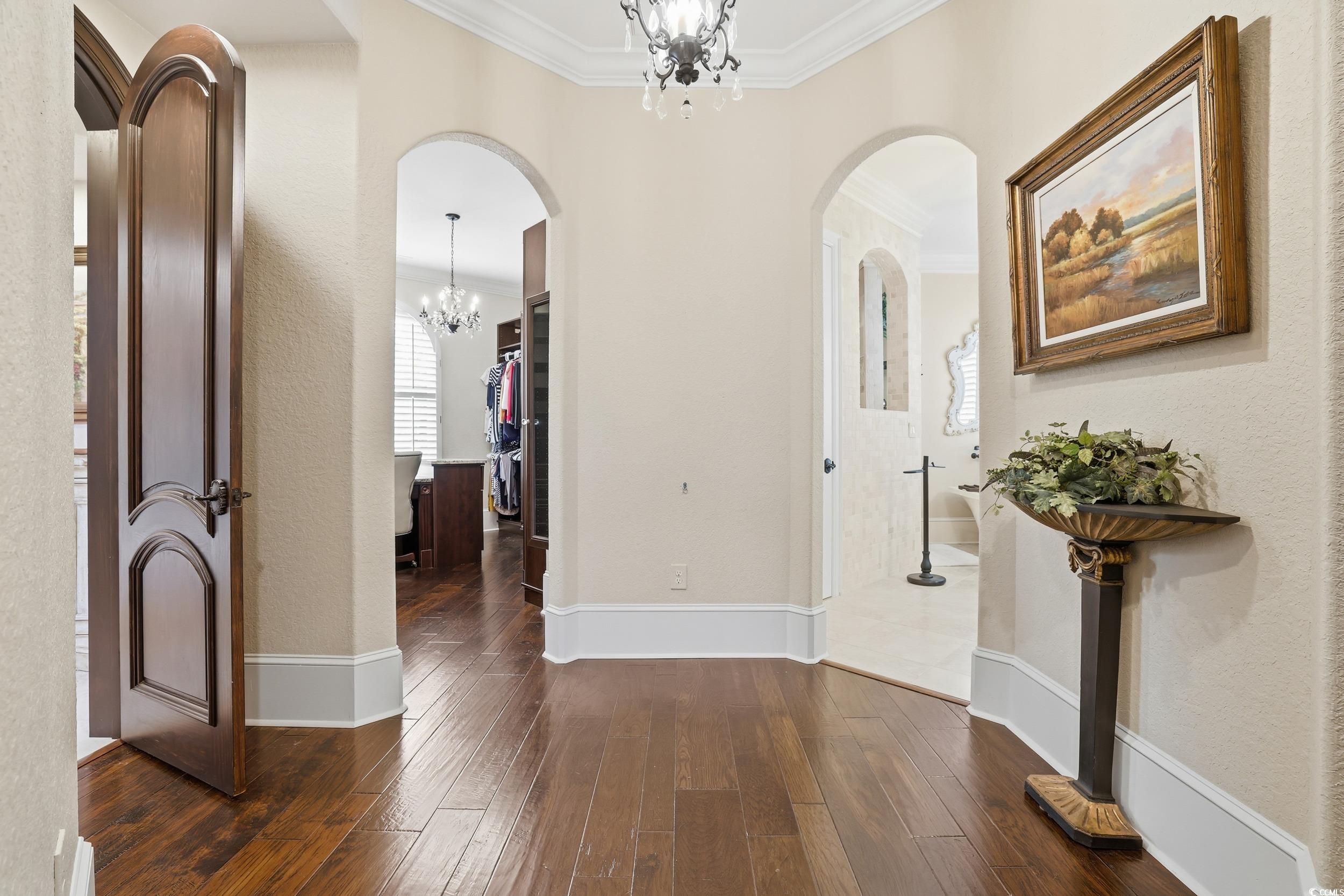9552 Lugano Court Myrtle Beach, SC 29579 - Photo 18 of 40 Corridor featuring a chandelier, arched walkways, dark wood finished floors, ornamental molding, and a textured wall