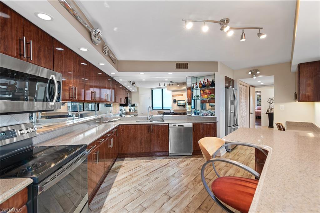 5555 Heron Point Drive, Unit 1202 Naples, FL 34108 - Photo 16 of 36 a kitchen with stainless steel appliances granite countertop a stove a sink dishwasher and a refrigerator with wooden floor