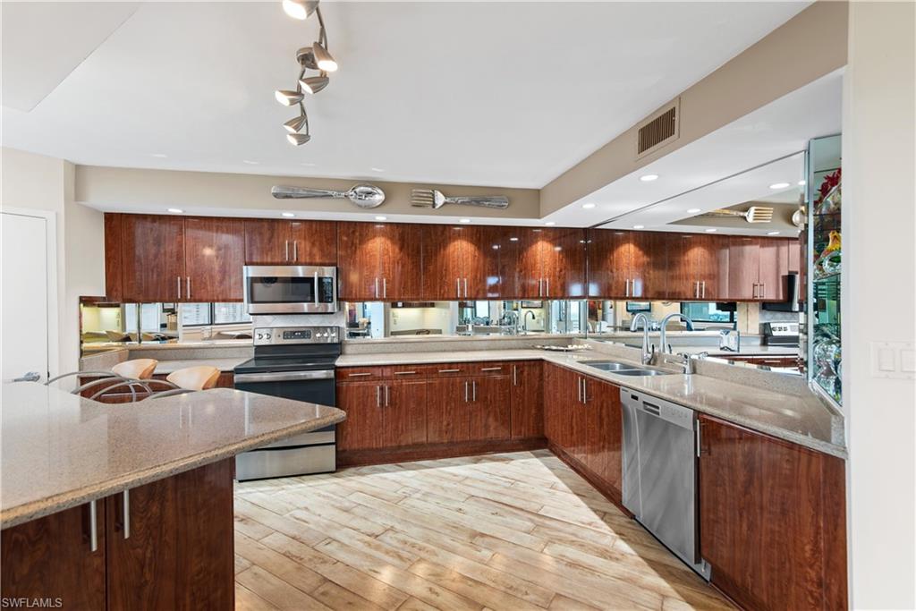 5555 Heron Point Drive, Unit 1202 Naples, FL 34108 - Photo 18 of 36 a kitchen with stainless steel appliances kitchen island granite countertop a sink and cabinets