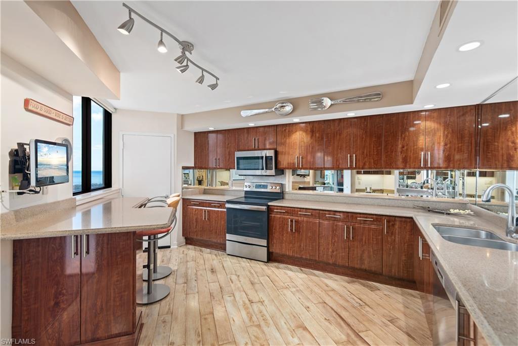 5555 Heron Point Drive, Unit 1202 Naples, FL 34108 - Photo 19 of 36 a large kitchen with wooden cabinets and stainless steel appliances