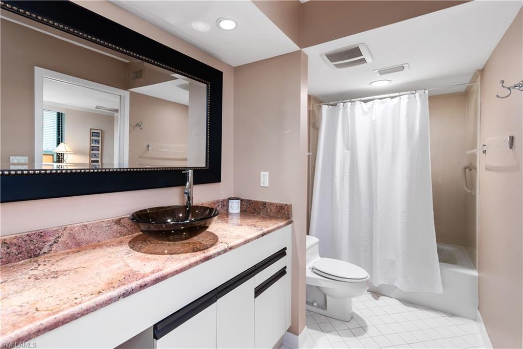 5555 Heron Point Drive, Unit 1202 Naples, FL 34108 - Photo 26 of 36 a bathroom with a granite countertop sink toilet and mirror