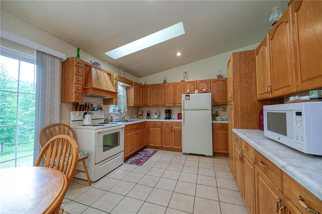 285 Glade Run Road Renfrew, PA 16053 - Photo 6 of 25 a kitchen with a refrigerator a stove top oven a sink dishwasher and white cabinets with wooden floor