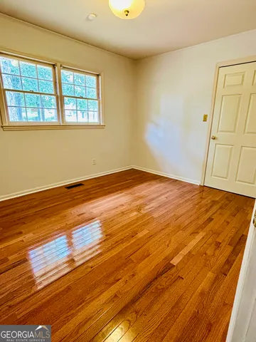 a view of an empty room with wooden floor and a window