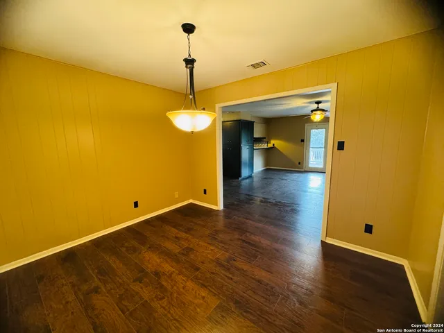 a view of a room with wooden floor and a ceiling fan