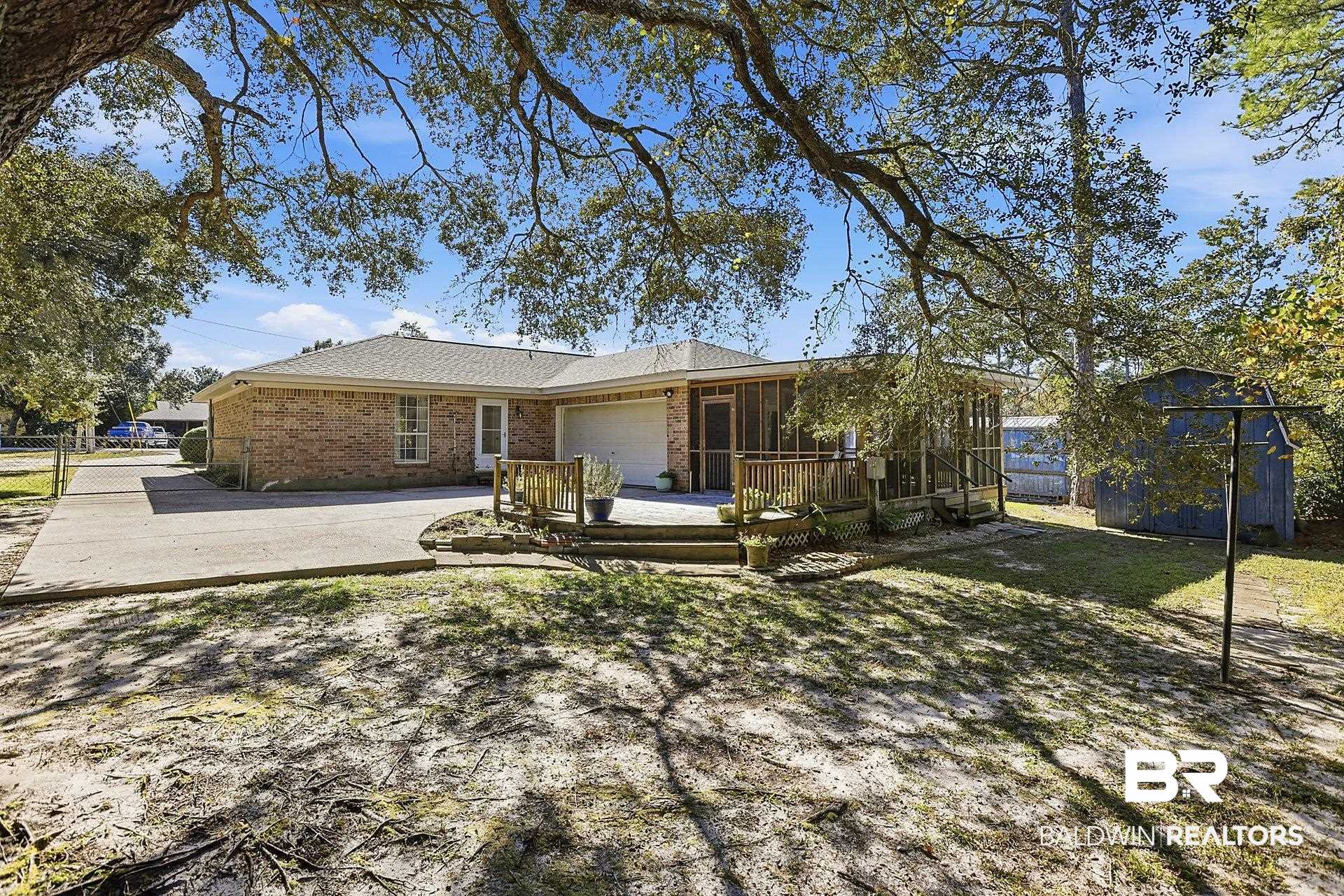 25793 Bonito Avenue Orange Beach, AL 36561 - Photo 6 of 27 Rear view of property featuring a wooden deck, brick siding, an attached garage, and driveway