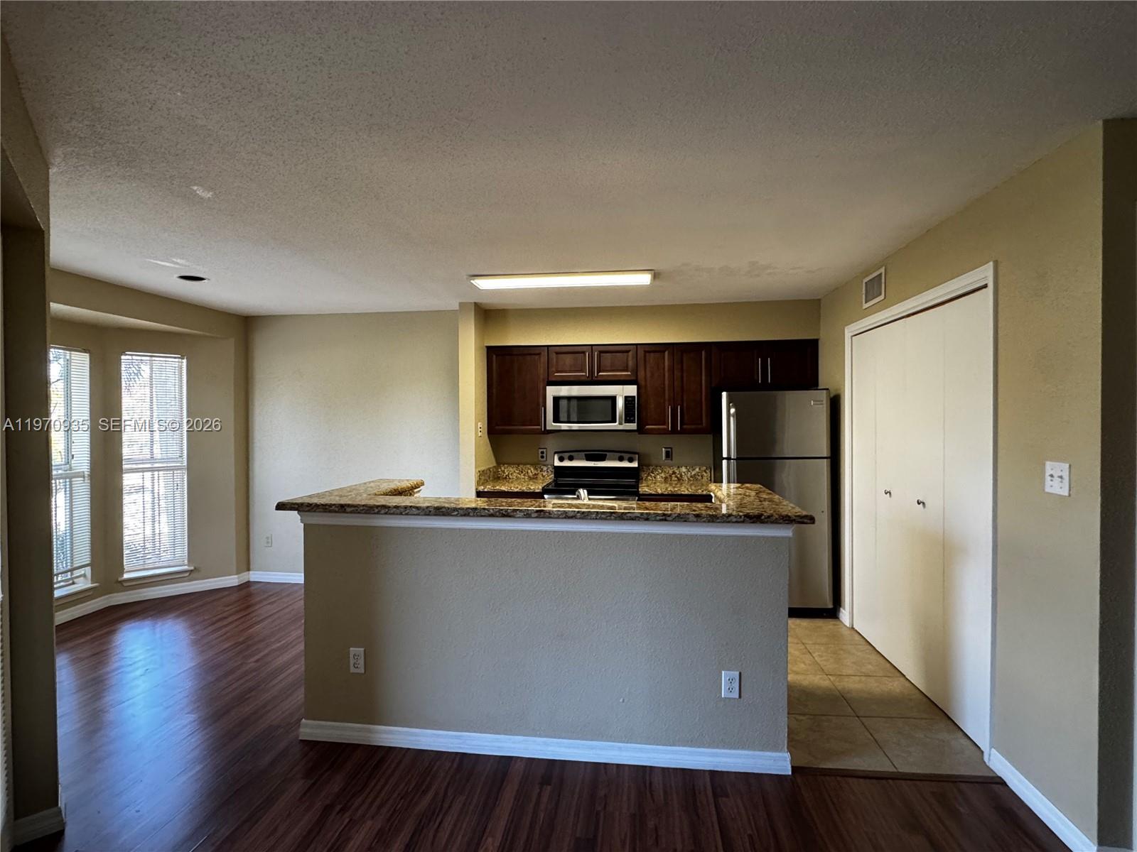 977 Riverside Drive, Unit 221 Coral Springs, FL 33071 - Photo 5 of 17 a view of kitchen with stainless steel appliances granite countertop a stove top oven a sink and dishwasher with wooden floor