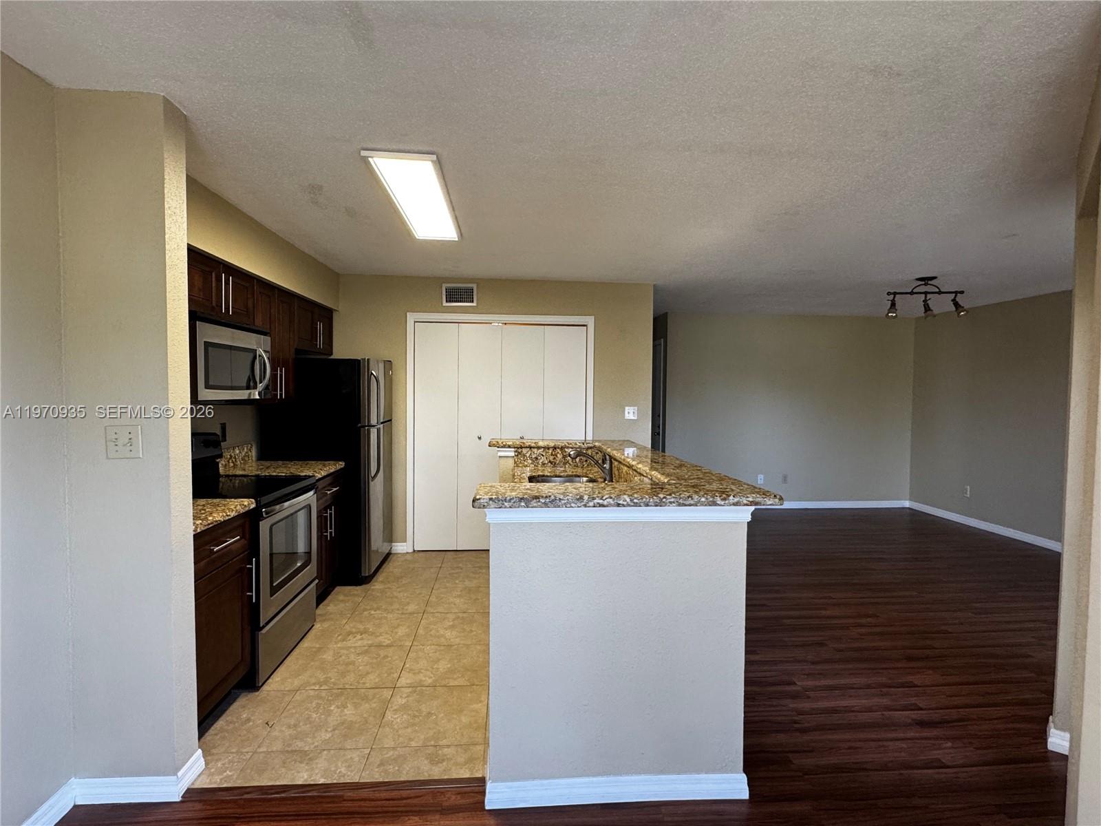 977 Riverside Drive, Unit 221 Coral Springs, FL 33071 - Photo 7 of 17 a kitchen with granite countertop a stove and a refrigerator
