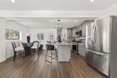 a kitchen with stainless steel appliances a dining table chairs refrigerator and cabinets