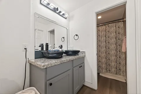 a bathroom with a granite countertop sink a mirror and shower