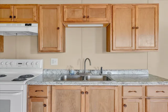 a kitchen with granite countertop a sink stove and cabinets