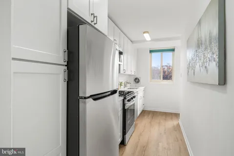 a kitchen with granite countertop a refrigerator a sink and white cabinets