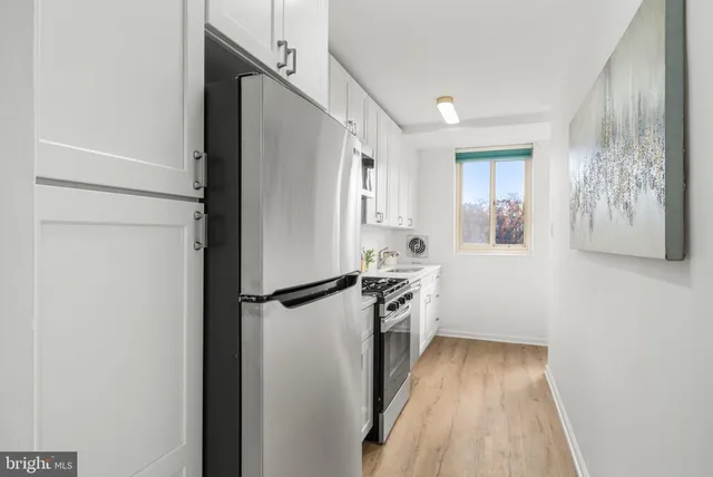 a kitchen with granite countertop a refrigerator a sink and white cabinets