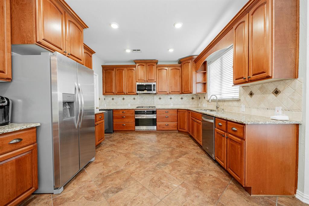 1805 Sumac Drive Flower Mound, TX 75028 - Photo 5 of 40 a kitchen with stainless steel appliances granite countertop a sink refrigerator and cabinets