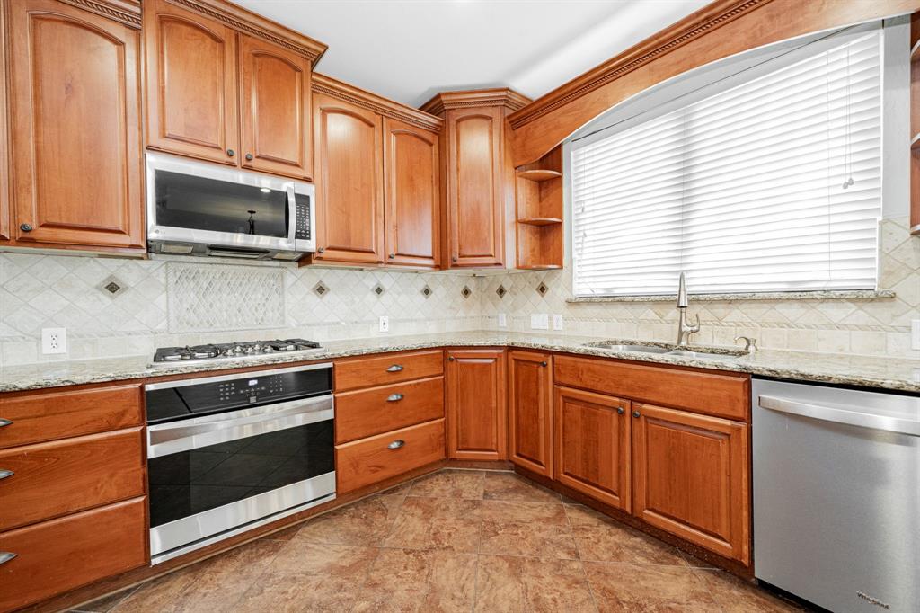 1805 Sumac Drive Flower Mound, TX 75028 - Photo 7 of 40 a kitchen with granite countertop cabinets stainless steel appliances and window