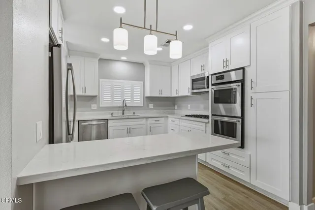 a kitchen with stainless steel appliances a refrigerator a sink and white cabinets