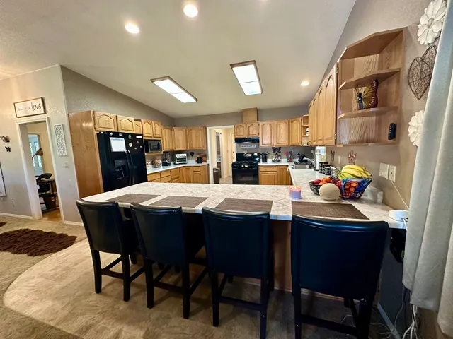 a kitchen with stainless steel appliances kitchen island granite countertop a table chairs sink refrigerator and microwave