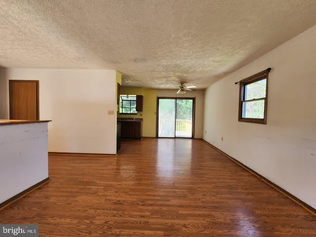 a view of an empty room with window and wooden floor