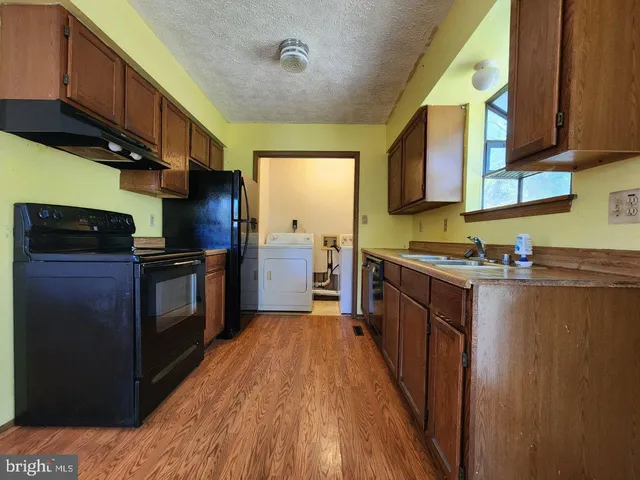 a kitchen with granite countertop wooden cabinets a stove top oven a sink and dishwasher