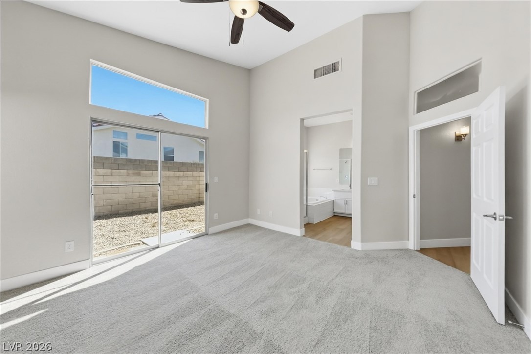1906 Cardinal Point Street Henderson, NV 89012 - Photo 12 of 20 High vaulted ceilings and tall windows elevate this carpeted main suite with sliding door access.