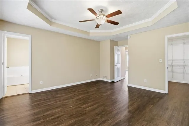 an empty room with wooden floor and ceiling fan