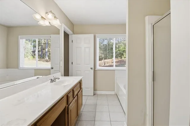 a spacious bathroom with a tub sink and a mirror