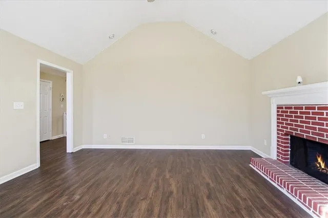 a view of an empty room with wooden floor fireplace and a window