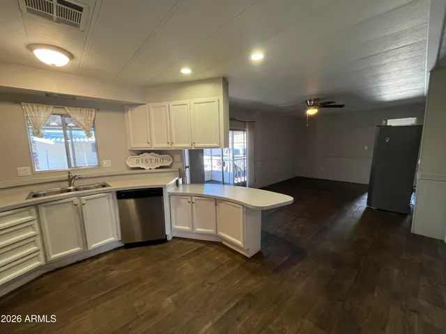 a kitchen with granite countertop a stove top oven a sink dishwasher and white cabinets with wooden floor