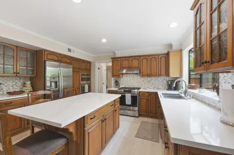 a kitchen with granite countertop a stove a sink a refrigerator dining table and chairs