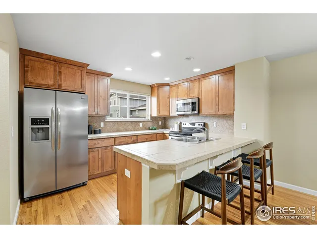 a kitchen with stainless steel appliances granite countertop a sink a stove a refrigerator with a dining table and chairs