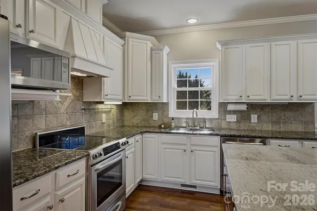a kitchen with stainless steel appliances granite countertop a sink a stove and a microwave